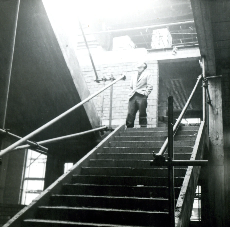 Black and white photo of Larkin on industrial staircase with metal railings, moody architectural scene, Brynmor Jones Library construction